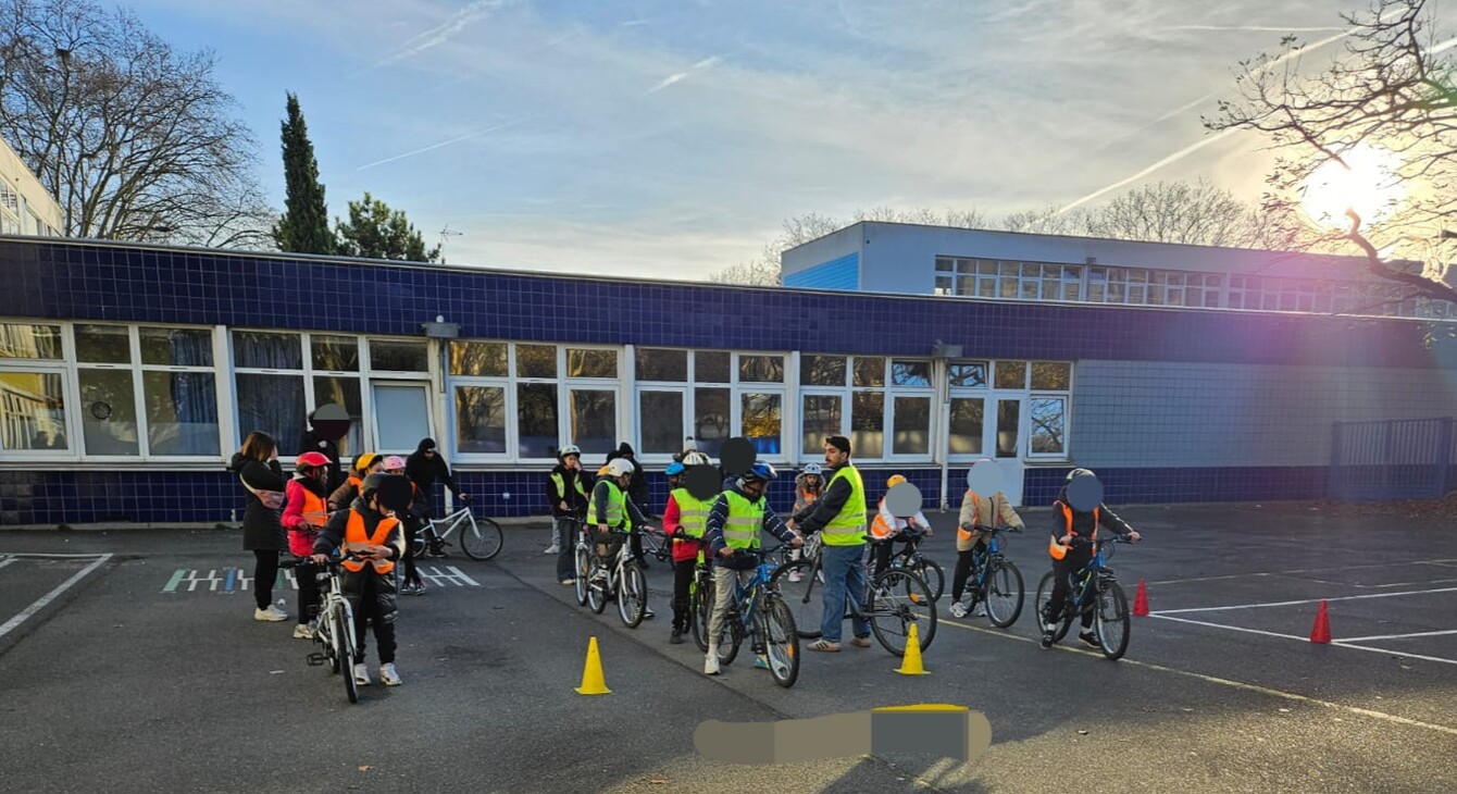 les élèves circule à vélo devant leurs établissement avec un ciel bleu ensoleillé