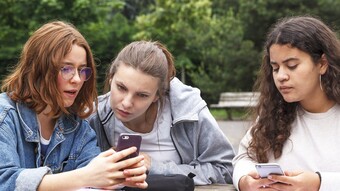 3 lycéennes regardant leur smartphone